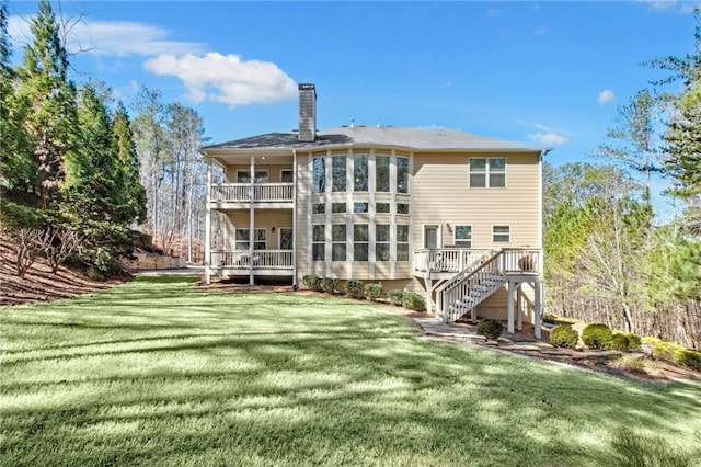 rear view of house with a chimney, stairway, a lawn, and a wooden deck