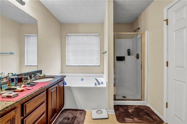full bath with a textured ceiling, a garden tub, vanity, and a stall shower