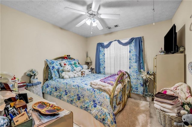 bedroom with a textured ceiling, visible vents, and ceiling fan