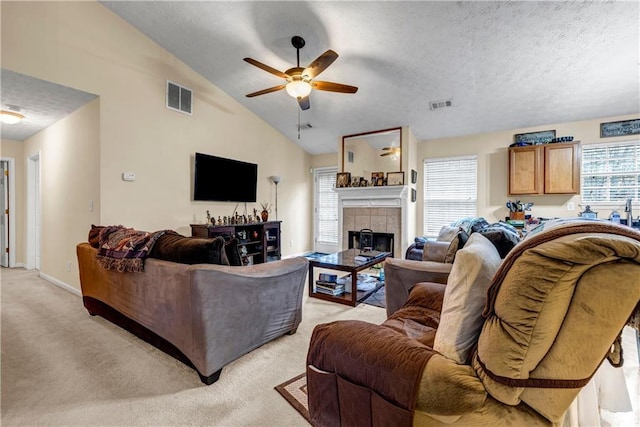 living area featuring a ceiling fan, visible vents, light carpet, and a textured ceiling