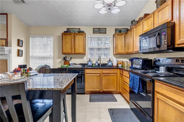 kitchen featuring black appliances, a wealth of natural light, light tile patterned floors, and a sink