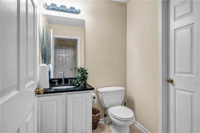 half bathroom featuring vanity, toilet, tile patterned flooring, and baseboards