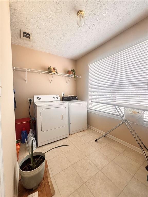 laundry room with washing machine and clothes dryer, laundry area, visible vents, baseboards, and a textured ceiling