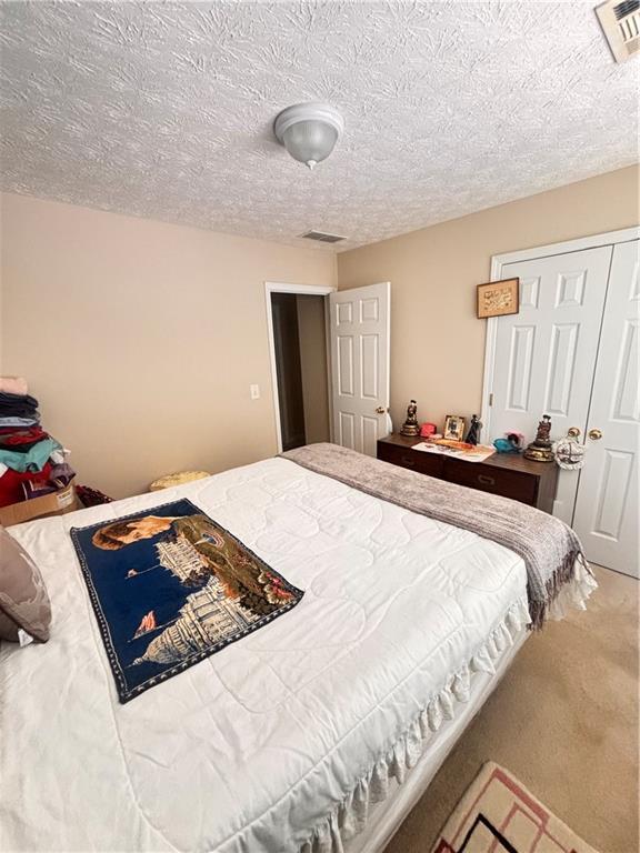 carpeted bedroom featuring visible vents and a textured ceiling