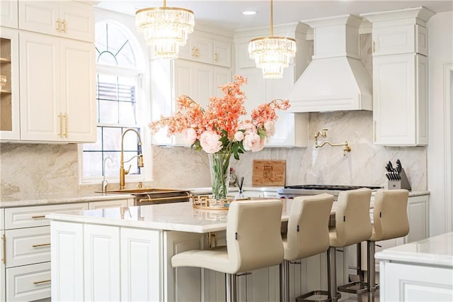 kitchen featuring white cabinetry, premium range hood, a center island, and a kitchen bar