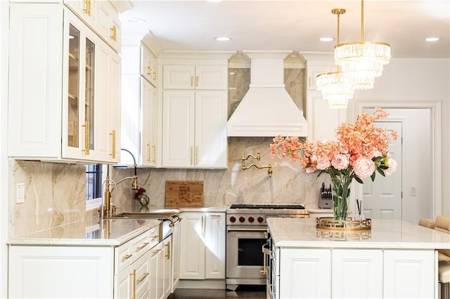 kitchen featuring high end range, decorative light fixtures, a center island, and custom range hood