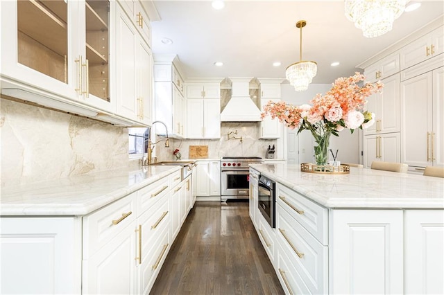 kitchen featuring premium range hood, sink, white cabinetry, hanging light fixtures, and stainless steel stove