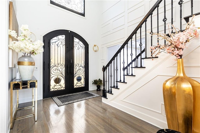 foyer featuring french doors, a towering ceiling, and wood-type flooring