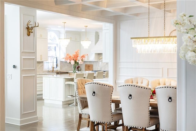 dining space with beamed ceiling, coffered ceiling, sink, and a notable chandelier