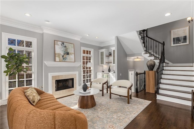 living area with crown molding, dark wood finished floors, recessed lighting, stairway, and a premium fireplace