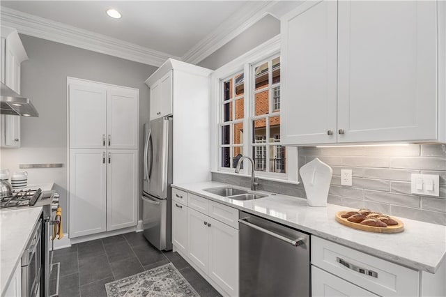 kitchen with a sink, white cabinetry, ornamental molding, appliances with stainless steel finishes, and decorative backsplash