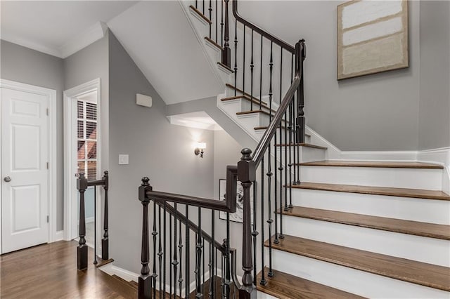 staircase with crown molding, baseboards, and wood finished floors