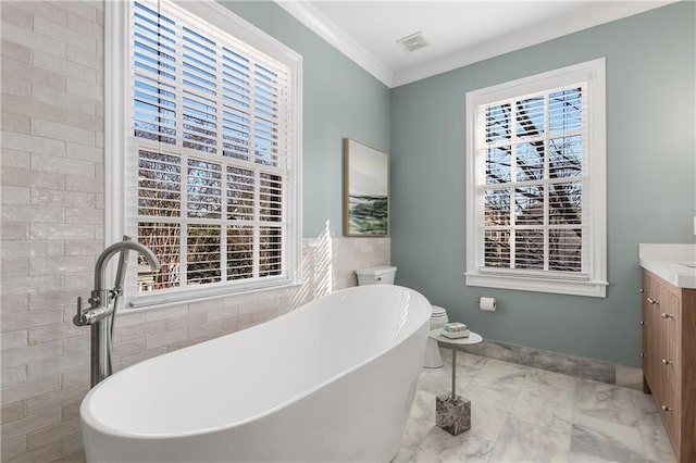 full bath featuring visible vents, a soaking tub, ornamental molding, marble finish floor, and vanity