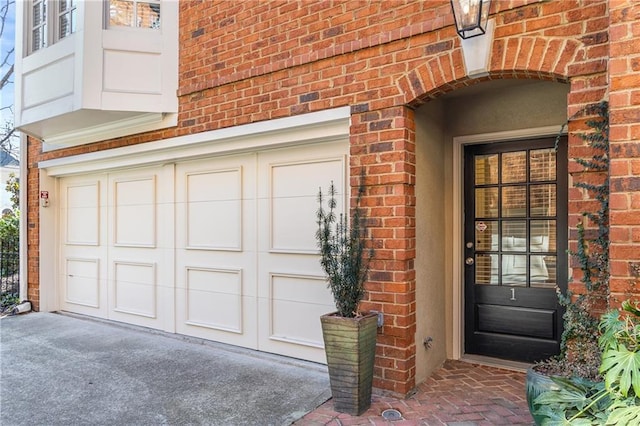 view of exterior entry featuring a garage and brick siding