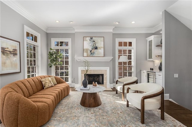 living area with a fireplace, ornamental molding, and wood finished floors