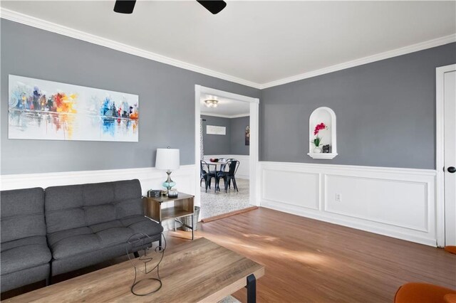 living room with ceiling fan, wood-type flooring, and crown molding