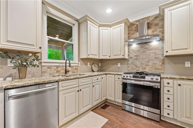 3232 Cates Ave NE, Brookhaven, GA 30319 - kitchen with appliances with stainless steel finishes, wall chimney range hood, a sink, cream cabinetry, and dark wood-style floors