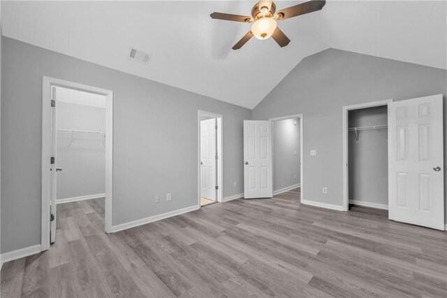 unfurnished bedroom featuring vaulted ceiling, a spacious closet, ceiling fan, light hardwood / wood-style floors, and a closet