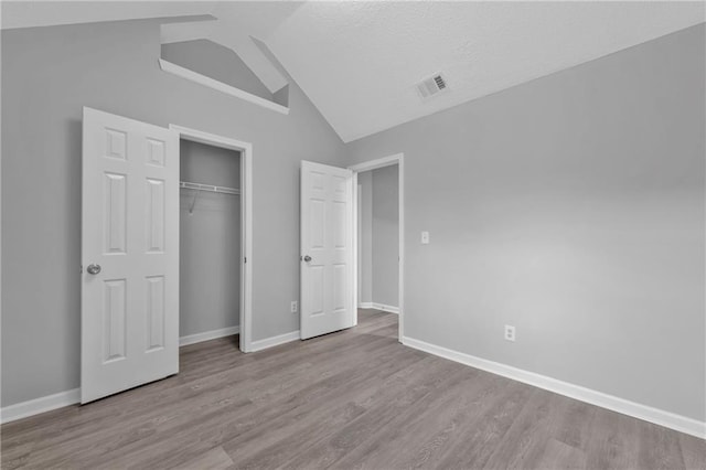 unfurnished bedroom featuring light hardwood / wood-style flooring, a closet, and vaulted ceiling