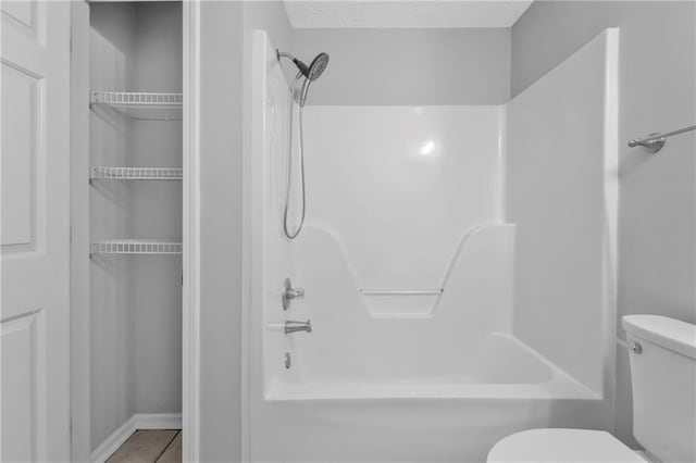 bathroom featuring tile patterned flooring,  shower combination, and toilet