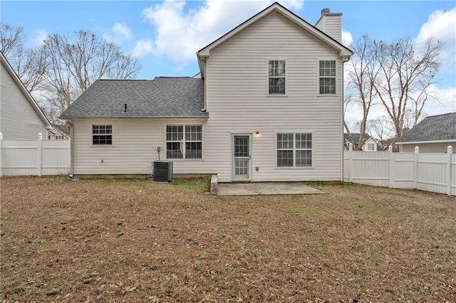 rear view of house with central AC, a patio area, and a lawn