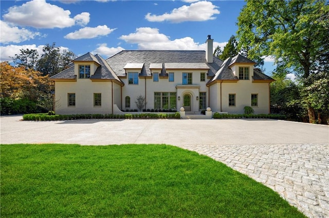 french provincial home with a front yard and a chimney