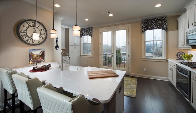 kitchen featuring sink, light stone counters, hanging light fixtures, a center island with sink, and stainless steel appliances