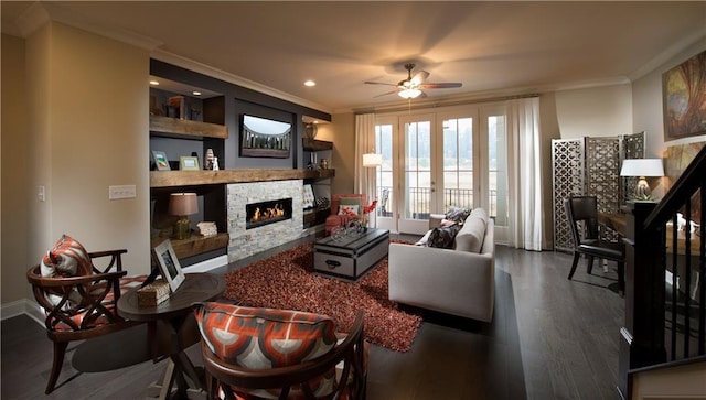 living room with french doors, a stone fireplace, ornamental molding, dark hardwood / wood-style flooring, and ceiling fan