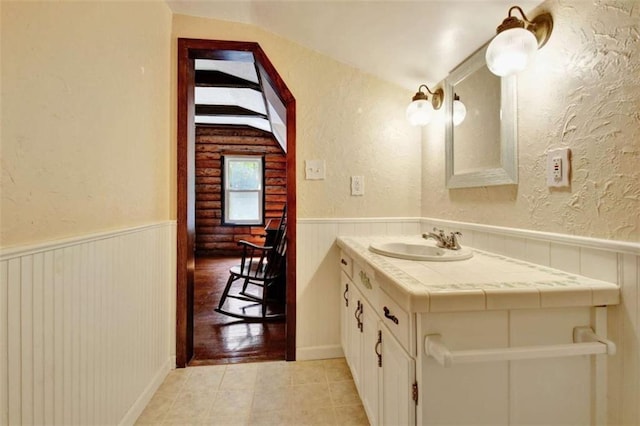 bathroom with tile patterned flooring, vanity, and vaulted ceiling