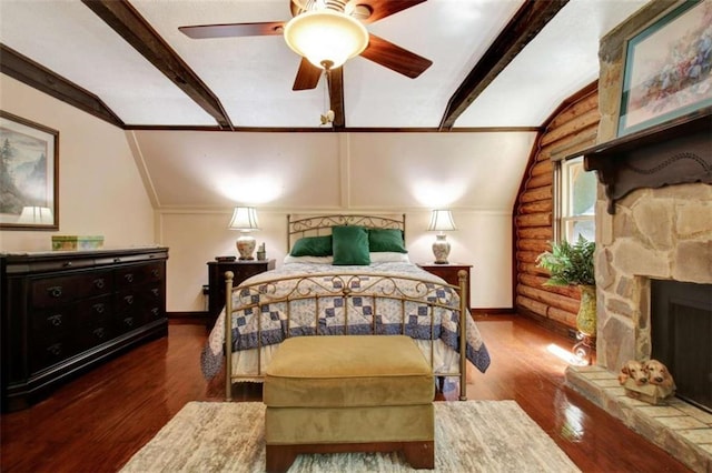 bedroom with ceiling fan, vaulted ceiling, dark hardwood / wood-style floors, and a stone fireplace