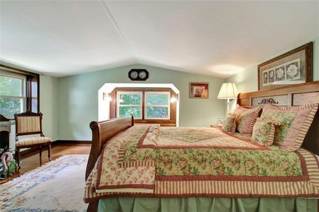 bedroom featuring hardwood / wood-style flooring, multiple windows, and vaulted ceiling