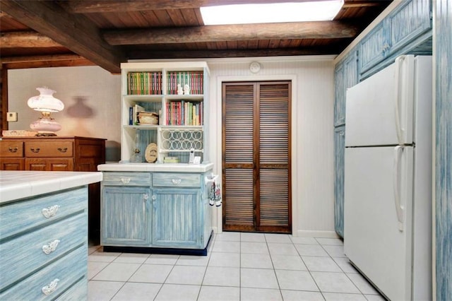 kitchen with white fridge, wooden ceiling, tile counters, and beamed ceiling