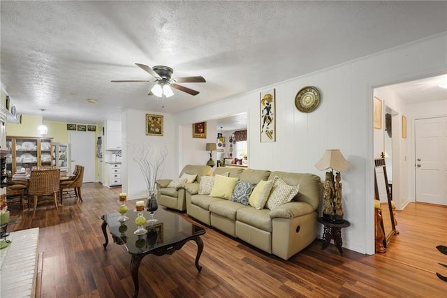 living room with ceiling fan, wood-type flooring, and a textured ceiling