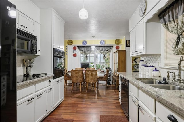 kitchen featuring pendant lighting, sink, dark wood-type flooring, black appliances, and white cabinets