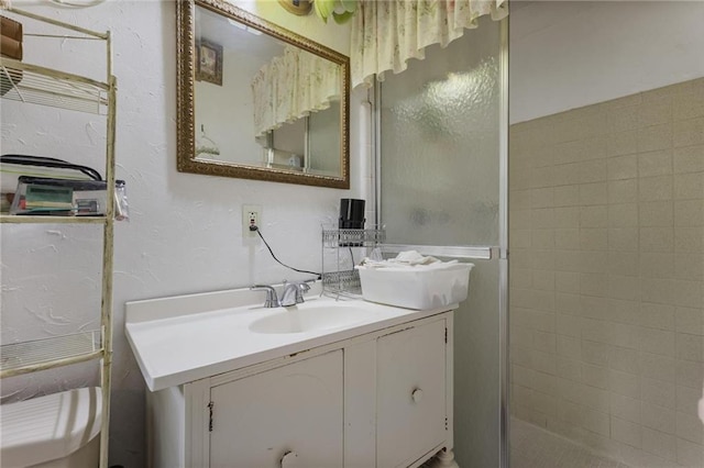 bathroom with a shower with door, vanity, and toilet