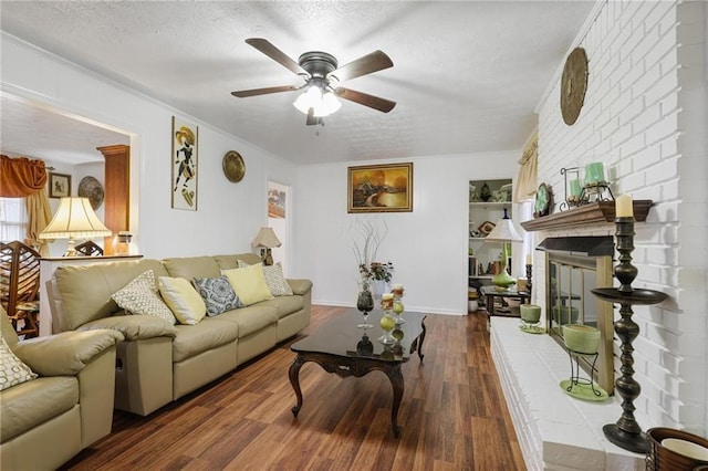 living room featuring dark wood-type flooring, ornamental molding, a brick fireplace, and a textured ceiling