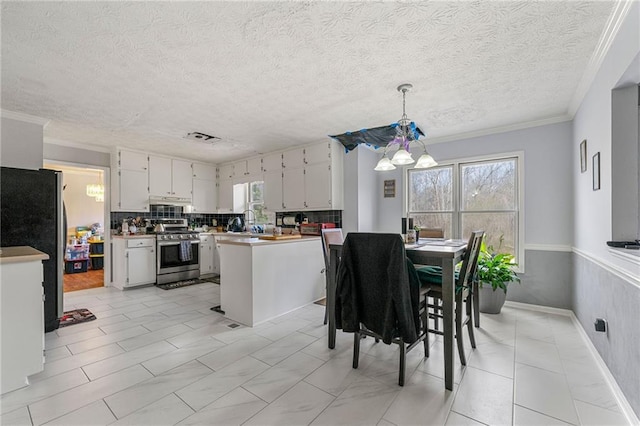kitchen featuring pendant lighting, ornamental molding, appliances with stainless steel finishes, backsplash, and an inviting chandelier