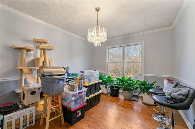 dining space featuring a notable chandelier, a textured ceiling, crown molding, and wood finished floors