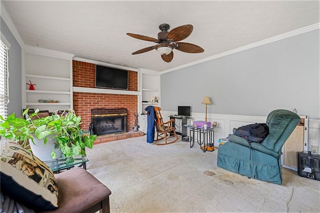 living room with built in shelves, carpet flooring, ornamental molding, wainscoting, and a brick fireplace
