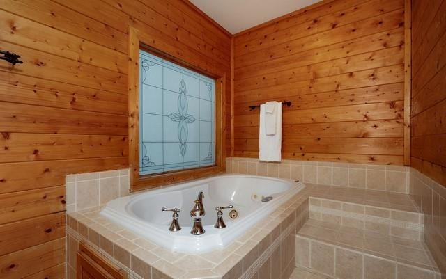 bathroom with tiled tub and wood walls