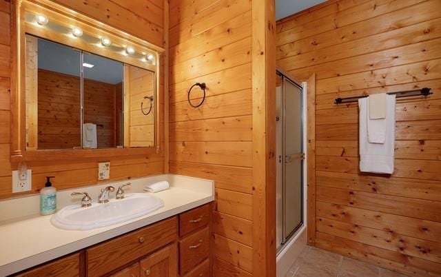 bathroom featuring vanity, wooden walls, a shower with shower door, and tile patterned flooring