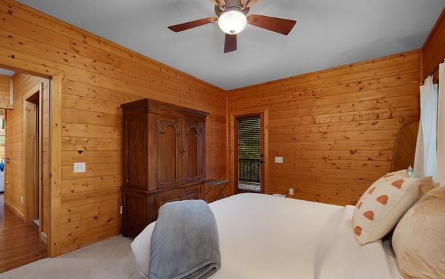 carpeted bedroom featuring ceiling fan and wooden walls