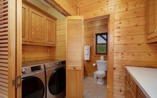 laundry area featuring cabinets, wood walls, light tile patterned floors, and washer and dryer