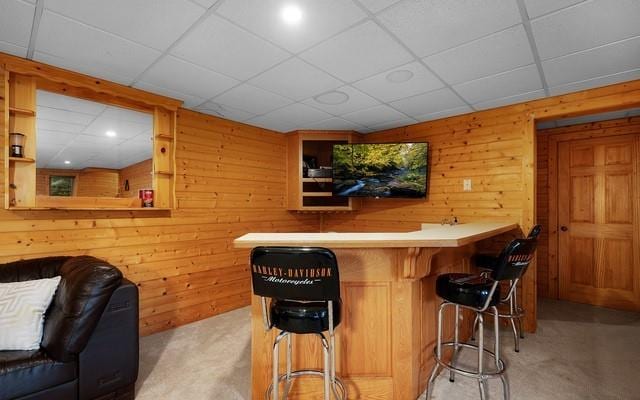 bar featuring a drop ceiling and wood walls