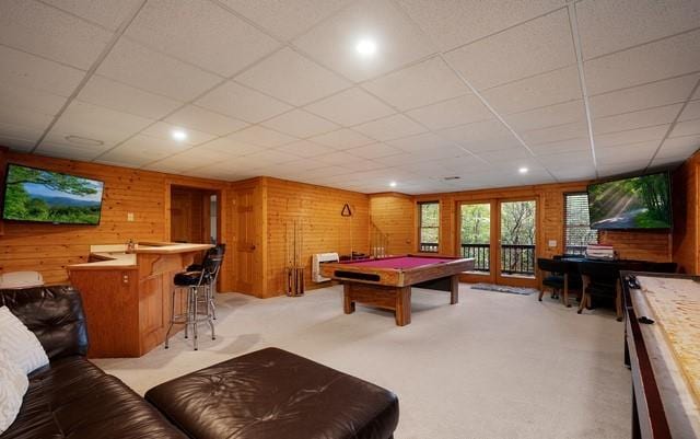 recreation room featuring wood walls, a paneled ceiling, bar area, light colored carpet, and billiards