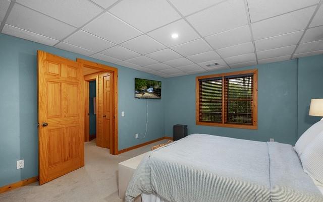 carpeted bedroom with a drop ceiling