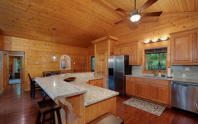 kitchen featuring wooden walls, stainless steel appliances, dark hardwood / wood-style floors, wooden ceiling, and a spacious island