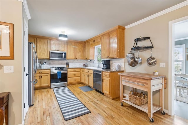 kitchen featuring light stone counters, appliances with stainless steel finishes, tasteful backsplash, light hardwood / wood-style flooring, and crown molding