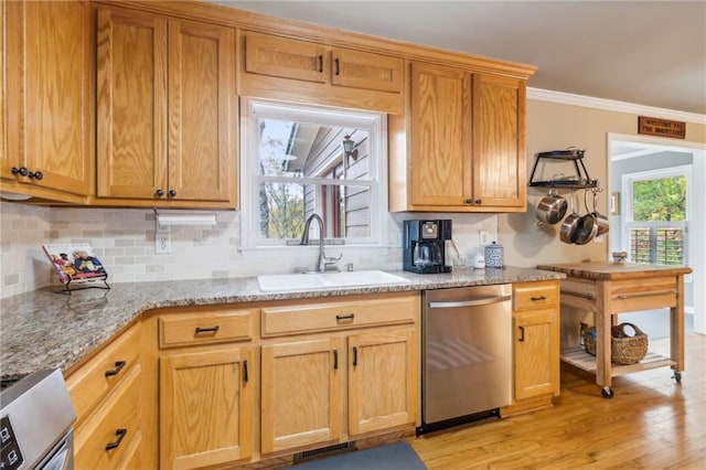 kitchen with sink, appliances with stainless steel finishes, ornamental molding, light stone countertops, and light hardwood / wood-style flooring