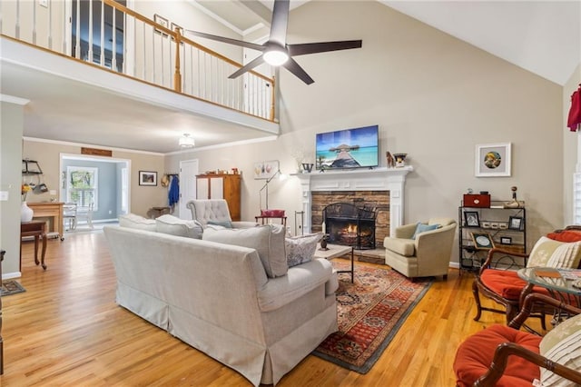 living room with high vaulted ceiling, a stone fireplace, hardwood / wood-style flooring, and crown molding